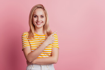 Portrait of adorable cheerful girl indicate forefinger empty space on pink background