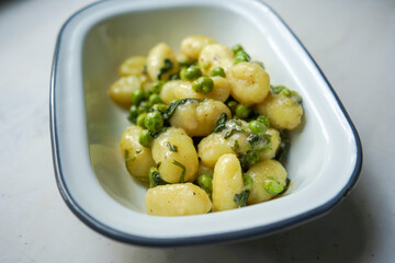 Homemade gnocchi with creamy sauce, green peas and spinach