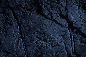 Toned rock texture. Cracked stone surface. Close-up. Dark blue rough background with copy space for design.