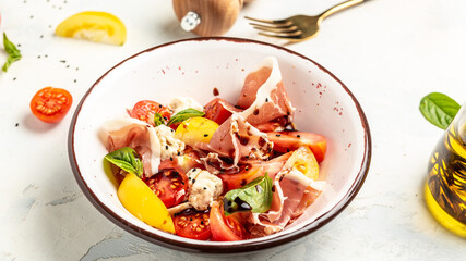 Salad with Prosciutto, ham jamon, tomatoes, cheese. Cold snacks. Food recipe background. Close up top view