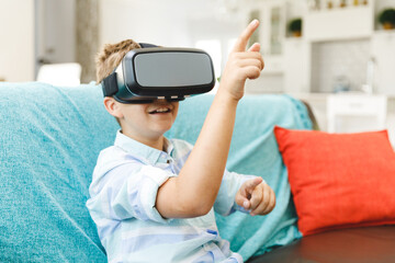 Caucasian boy sitting on couch and using vr headset in living room