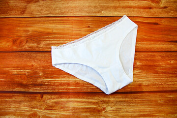 Naklejka premium Cotton white panties on wooden background with a copy space