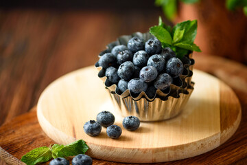 Juicy and fresh blueberries with green mint leaves on wooden table. Selective focus