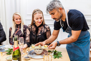 Latin cook serving food to clients during private dinner