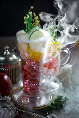 Fruit cocktail, in a glass with natural healthy fruits on a table with kitchen accessories.