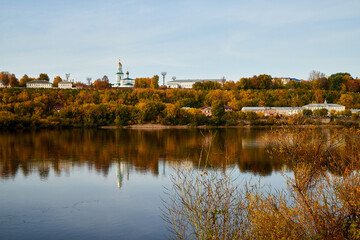 Natural view of the landscape with a lake or river and a city on the other side on the yellow shore in autumn day with blue sky