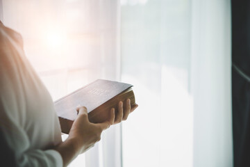 Christian teenage girl holds bible in her hands.