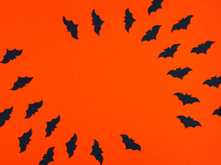 Silhouette of bats circling on orange. Background for Halloween party flyers. Place for your text. Flat layout.