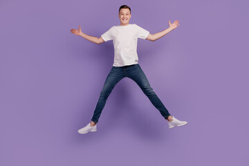Fototapeta na wymiar Portrait of crazy dreamy positive guy jump have fun on purple background
