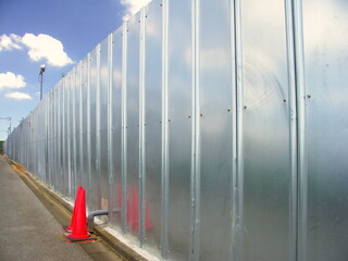 工事現場のフェンスと赤いパイロンのある風景
