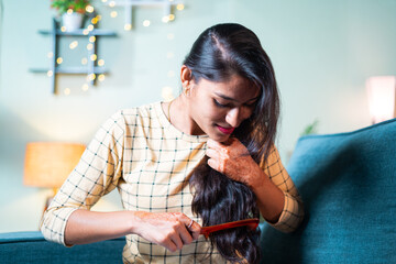 Young Indian girl on sofa combing her long hairs - concept of woman getting ready and daily rituals.
