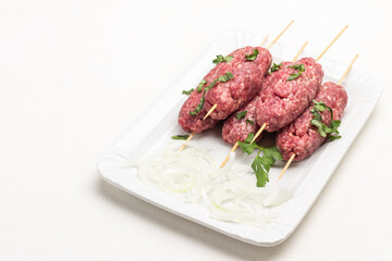 Raw minced meat on wooden skewers