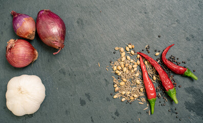 Shallot, Spices, Garlic and Chilli Peppers on Black Slate Tile