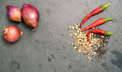 Shallot, spices and Chilli Peppers on Black Slate Tile