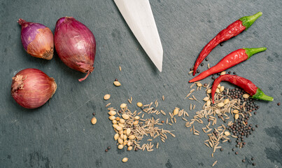 Chef knife with shallot spices and Chilli Peppers on Black Slate Tile
