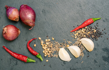 Spices, Garlic, shallot and Chilli Peppers on Black Slate Tile