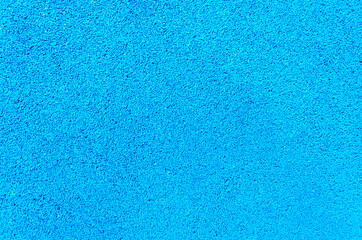 Fototapeta na wymiar Rubber crumb artificial coating of modern multifunctional sports ground. Safe soft anti-slip floor for playground. Blue textured background.
