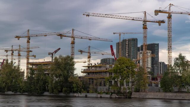 Construction cranes are working on the construction of a residential quarter on the river bank on the site of the former industrial zone,time lapse