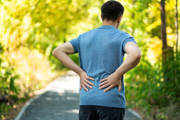 Back pain when walking outdoors, man with kidney inflammation on nature background