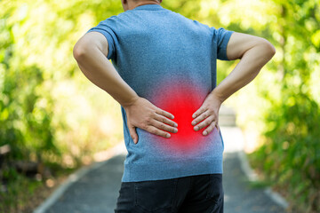 Back pain when walking outdoors, man with kidney inflammation on nature background