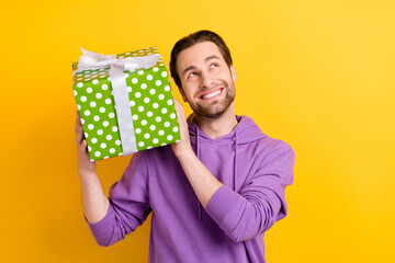 Photo of young man happy positive smile shake present box interested dream isolated over yellow color background