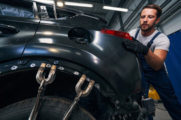 Screw clamps flattening car body while technician adjusting taillight