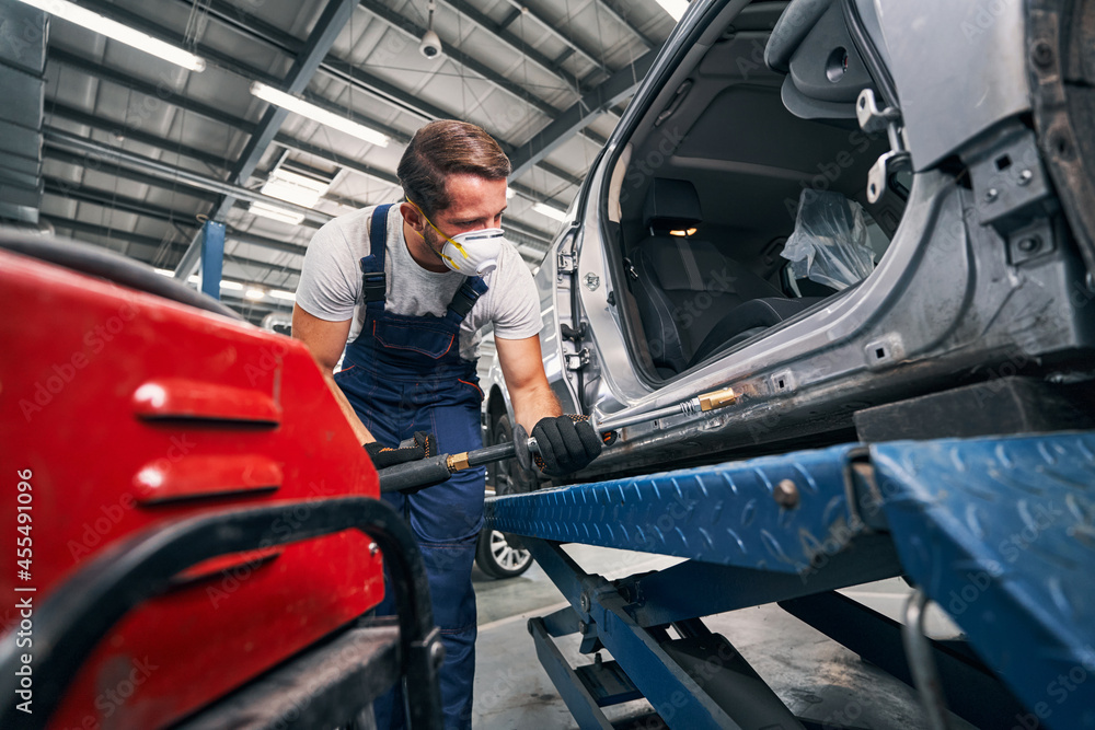 Wall mural Repairman peening car with tool for removing dents