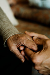 young man holds the hand of an old woman