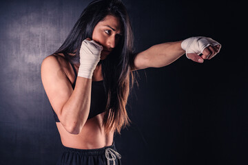 Young latin woman practicing boxing and kickboxing. She scores a direct punch with her fist. Sport, fitness, fitness, training concept.