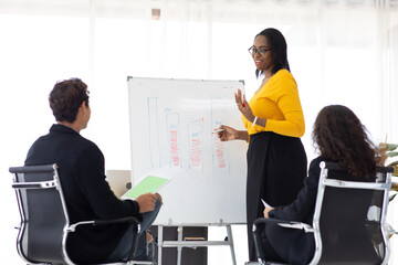 African American female manager speaker pointing whiteboard presentation to diverse employees in...