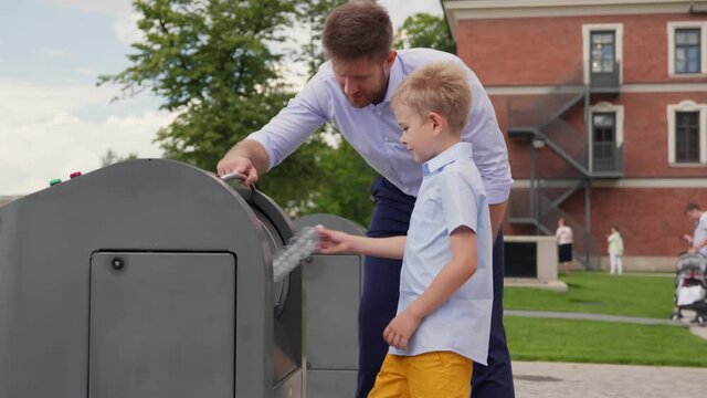 Father and son throwing out empty bottle to trash bin outdoors