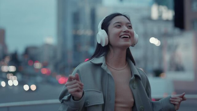 Joyful woman in headphones dancing and walking on street