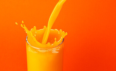 Fototapeta na wymiar Orange juice pouring into glass with splash