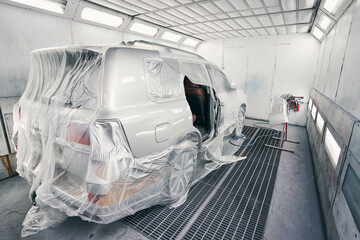 Van covered in film standing in spray booth