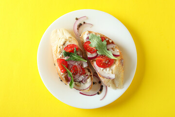 Plate with bruschetta snacks on yellow background