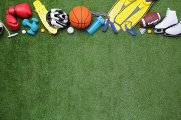 Different sport equipment on green grass, flat lay. Space for text