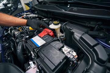 Person checking the car battery under bonnet