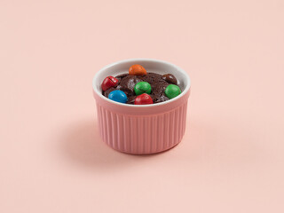 brownie cake in pink ceramic cup with colorful chocolate candy topping on pastel pink table top....