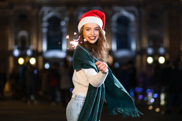 beautiful girl celebrating new year outdoors with sparkler in he