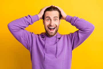Fototapeta na wymiar Photo of funky positive astonished guy hands head open mouth wear violet hoodie isolated yellow color background