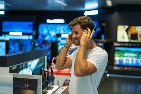 Happy buyer choosing headphones in store