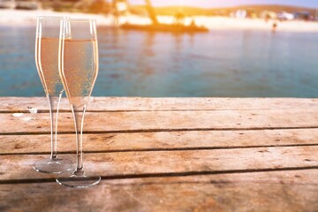 Two glasses of cold rose wine on sandy beach in sunny day,