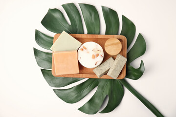 Wooden tray with eco friendly personal care products and green leaf on white background, top view