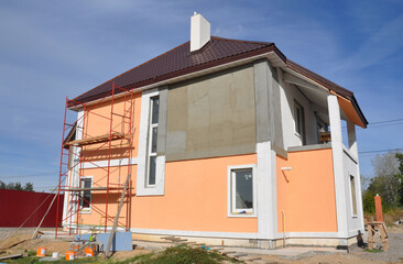 Home exterior renovation and outside house walls painting. A close-up of a house under renovation with scaffolding for rendering, plastering and painting.
