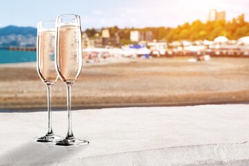 Two glasses of cold rose wine on sandy beach in sunny day,
