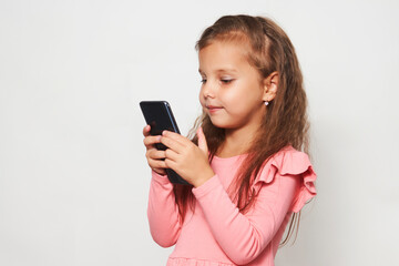 Fototapeta premium Portrait of a little girl using cell phone against white background