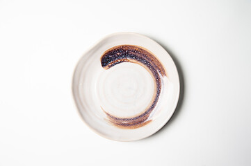 Ceramic and crafted plate with zen paint pattern on white, view from above