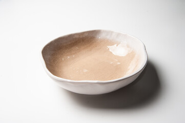 Close of light brown ceramic free form plate on white backdrop