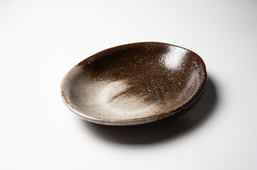 Close of deep brown shading ceramic and oval plate on white backdrop