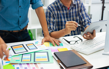 Mobile app designers discuss interface layout designs and test the functionality of mobile applications on tablets. © Wasan